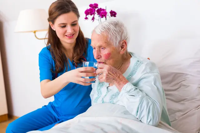 Caregiver Bringing Water To The Senior Woman 640